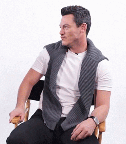 A Man Is Sitting In A Chair Wearing A Watch GIF