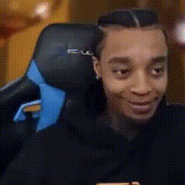 A Man Is Sitting In A Chair With A Blue Headrest And Smiling . GIF