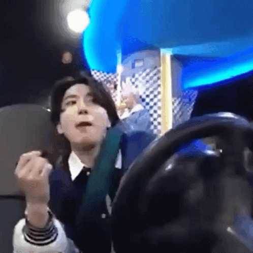 A Man Is Sitting In A Chair With A Steering Wheel In Front Of Him And Making A Funny Face . GIF