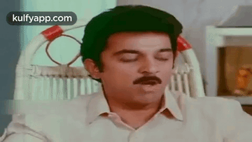 A Man Is Sitting In A Chair With His Eyes Closed . GIF