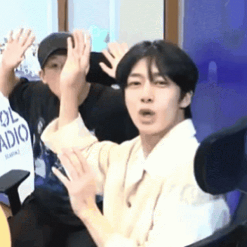 A Man Is Sitting In A Chair With His Hands Up . GIF