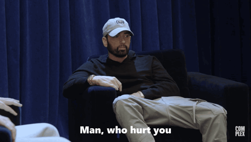 A Man Is Sitting In A Chair With The Words Man Who Hurt You Below Him GIF