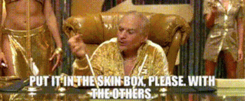 A Man Is Sitting In A Chair With The Words Put It In The Skin Box Please With The Others Behind Him GIF
