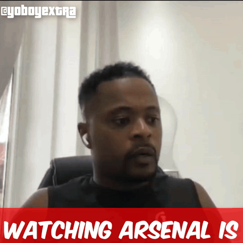 A Man Is Sitting In A Chair With The Words Watching Arsenal Is Behind Him GIF