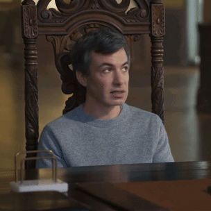 A Man Is Sitting In A Chair With Uhh Sure Written On The Table GIF