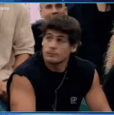 a man is sitting in a crowd of people and looking at the camera .