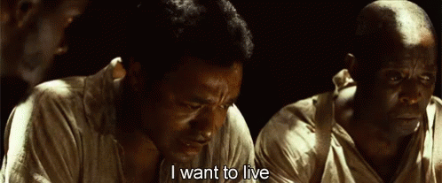 A Man Is Sitting In A Dark Room And Saying I Want To Live . GIF