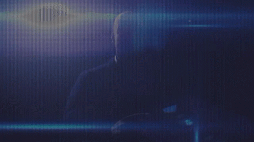 a man is sitting in a dark room with a blue light behind him