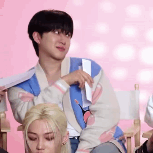A Man Is Sitting In A Director 'S Chair Holding A Piece Of Paper In His Hand . GIF