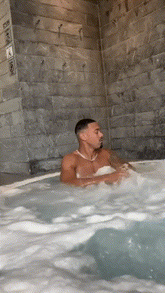 A Man Is Sitting In A Hot Tub With A Bikini On . GIF
