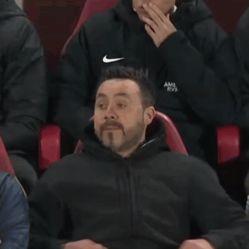 A Man Is Sitting In A Red Chair With His Face Covered . GIF