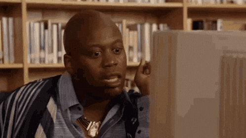 a man is sitting in front of a computer in a library .