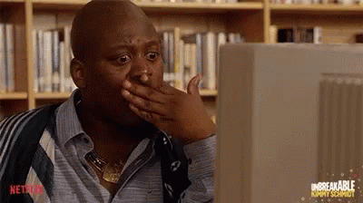 A Man Is Sitting In Front Of A Computer Screen And Covering His Mouth With His Hand . GIF
