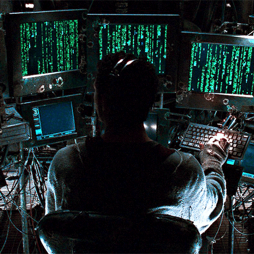 A Man Is Sitting In Front Of A Computer Screen That Says " Matrix " On It GIF