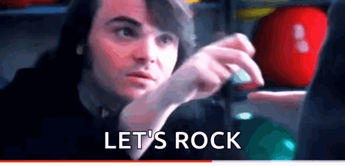 A Man Is Sitting In Front Of A Computer With The Words Let 'S Rock Written On The Bottom . GIF
