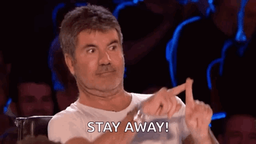 A Man Is Sitting In Front Of A Crowd Making A Funny Face And Pointing At Something . GIF