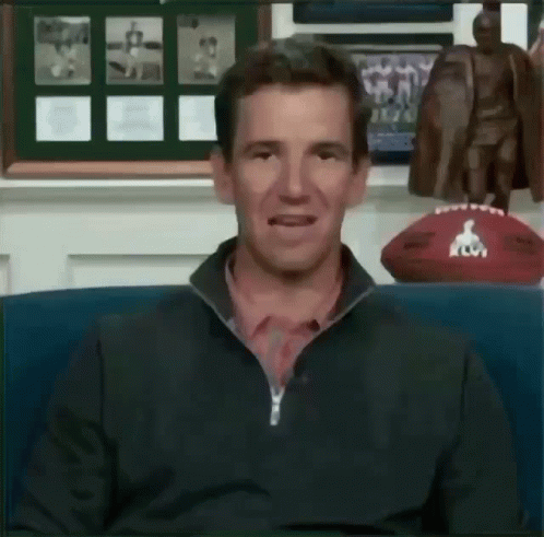 a man is sitting in front of a football and a statue of a man .