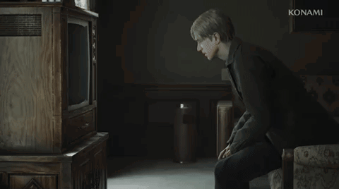 A Man Is Sitting In Front Of A Konami Television In A Dark Room GIF