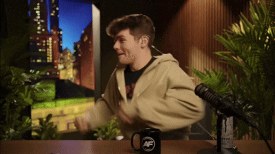 A Man Is Sitting In Front Of A Microphone And A Mug That Says Af On It GIF