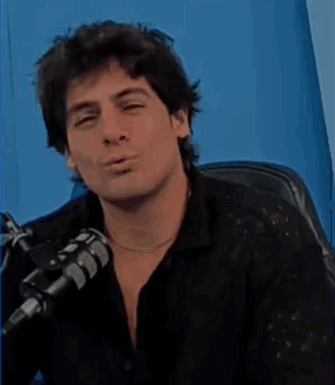 a man is sitting in front of a microphone and looking down .