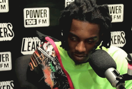 A Man Is Sitting In Front Of A Microphone In Front Of A Power 106 Fm Sign GIF