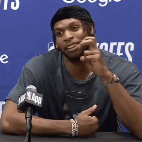 a man is sitting in front of a microphone that says nba app