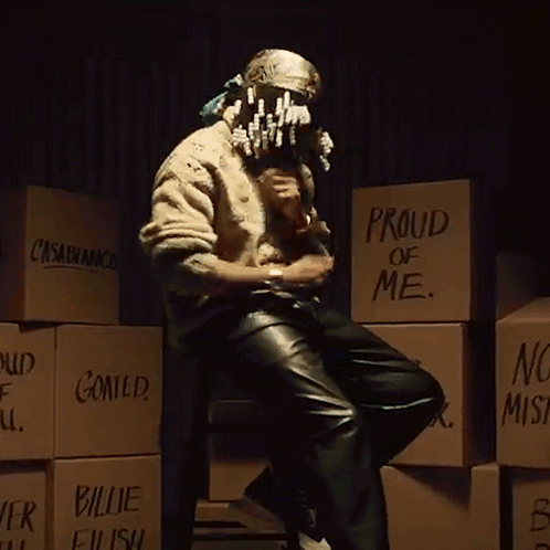 A Man Is Sitting In Front Of A Stack Of Boxes That Say Proud Of Me GIF