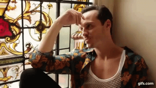 A Man Is Sitting In Front Of A Stained Glass Window And Looking Out . GIF