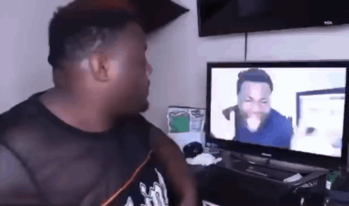 A Man Is Sitting In Front Of A Television Watching A Video . GIF