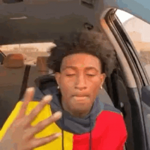 A Man Is Sitting In The Back Seat Of A Car With His Eyes Closed And A Hand Reaching Out Towards Him . GIF