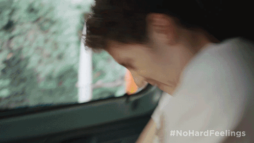 A Man Is Sitting In The Back Seat Of A Car With His Head Down GIF
