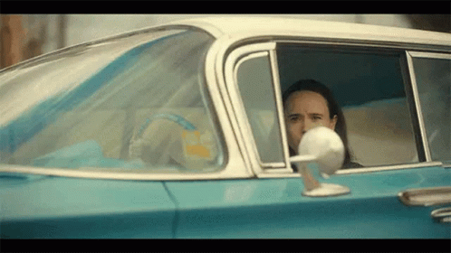 A Man Is Sitting In The Driver 'S Seat Of A Blue Car . GIF