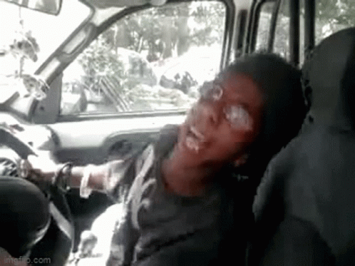 A Man Is Sitting In The Driver 'S Seat Of A Car And Making A Funny Face . GIF