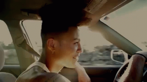 A Man Is Sitting In The Driver 'S Seat Of A Car Looking Out The Window . GIF