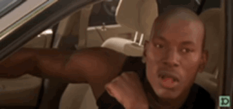 A Man Is Sitting In The Driver 'S Seat Of A Car Making A Face . GIF