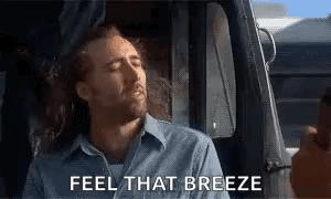 A Man Is Sitting In The Driver 'S Seat Of A Truck With His Eyes Closed And The Words `` Feel That Breeze '' . GIF
