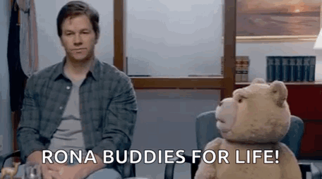 A Man Is Sitting Next To A Teddy Bear In A Chair And Says `` Rona Buddies For Life '' . GIF