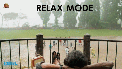 A Man Is Sitting On A Balcony With His Feet Up And The Words Relax Mode Behind Him GIF