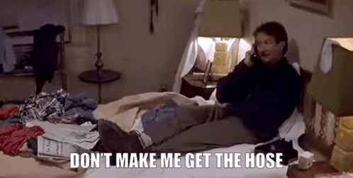 A Man Is Sitting On A Bed Talking On A Cell Phone . GIF