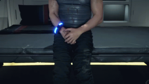 A Man Is Sitting On A Bed With His Hands On His Pants GIF