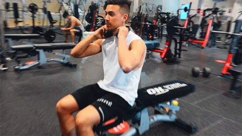 A Man Is Sitting On A Bench In A Gym That Says Orlstrom GIF