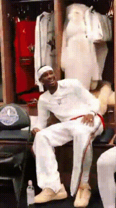 A Man Is Sitting On A Bench In A Locker Room Wearing White Pants GIF
