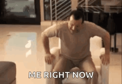 A Man Is Sitting On A Chair With His Legs Crossed And The Words `` Me Right Now '' Written On The Screen . GIF
