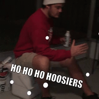 A Man Is Sitting On A Cooler With The Words Ho Ho Ho Hoosier Written On His Leg GIF