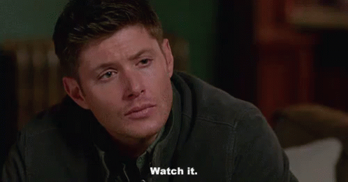 A Man Is Sitting On A Couch And Saying `` Watch It '' While Looking At The Camera . GIF
