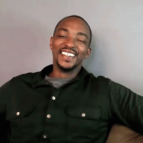 A Man Is Sitting On A Couch And Smiling With His Eyes Closed . GIF