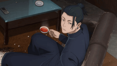 A Man Is Sitting On A Couch Drinking A Cup Of Coffee GIF