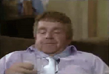 A Man Is Sitting On A Couch Drinking A Glass Of Water . GIF
