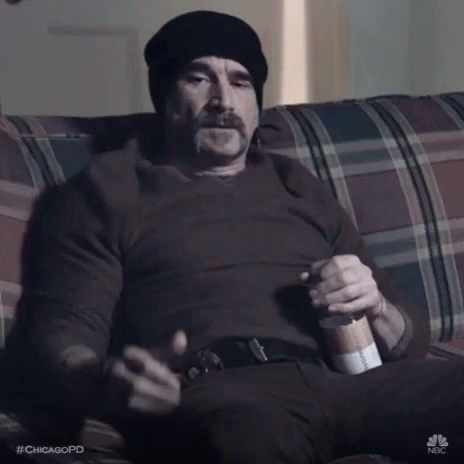 A Man Is Sitting On A Couch Giving A Thumbs Up Sign While Holding A Bottle Of Beer . GIF