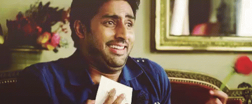 A Man Is Sitting On A Couch Holding A Piece Of Paper And Making A Funny Face . GIF
